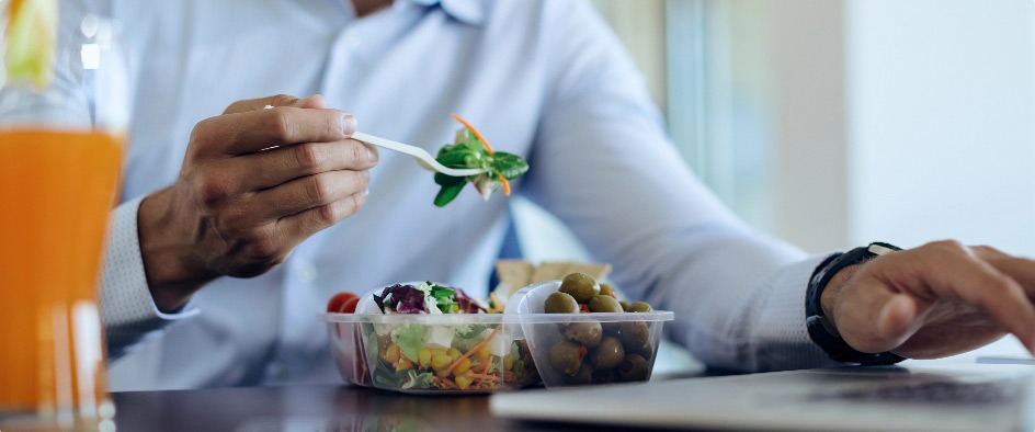 Man eating health food using laptop